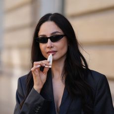 street style shot of woman in sunglasses applying lip balm