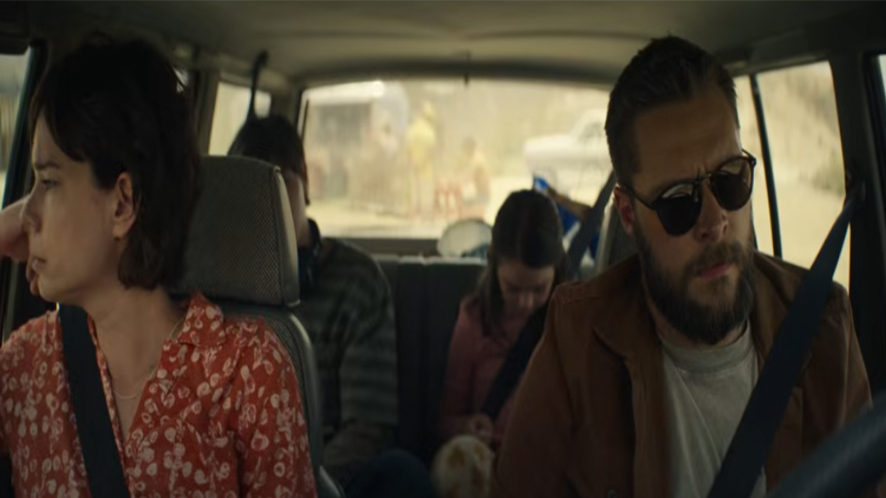 Two adults in the front seat of a car with two kids in the back.