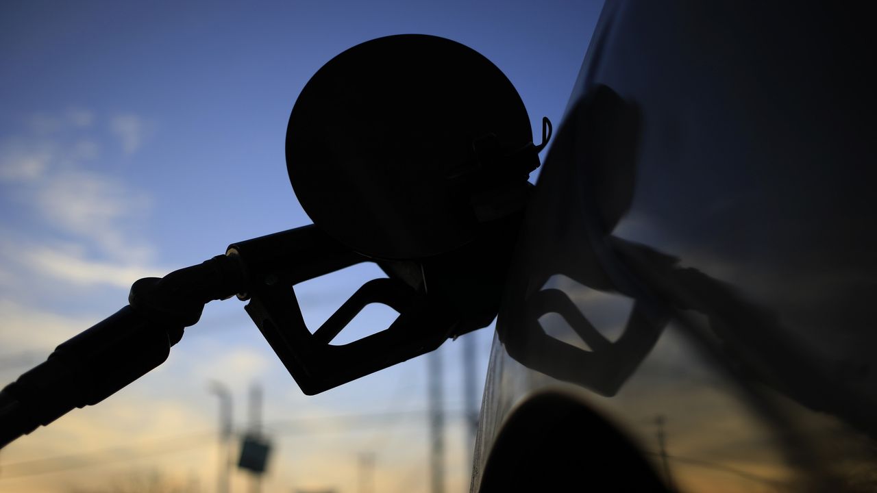 The nozzle of a gas pump is plugged into the tank of a car.