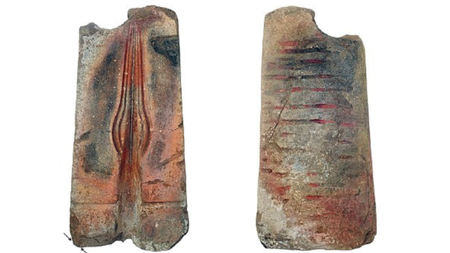 An image of two halves of a spearhead mold, the rock gray and red with the left open half showing the mold for a teardrop shaped spearhead. 