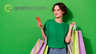 Woman looking at her phone while holding multiple shopping bags against a green background