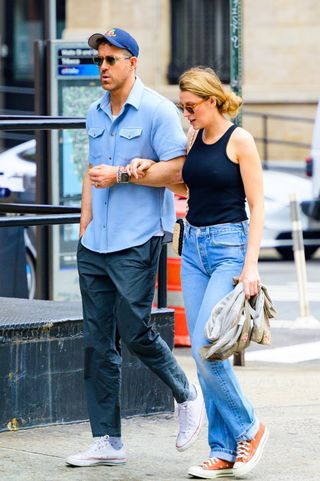 Blake Lively wears a navy tank top and jeans with Converse sneakers walking with Ryan Reynolds