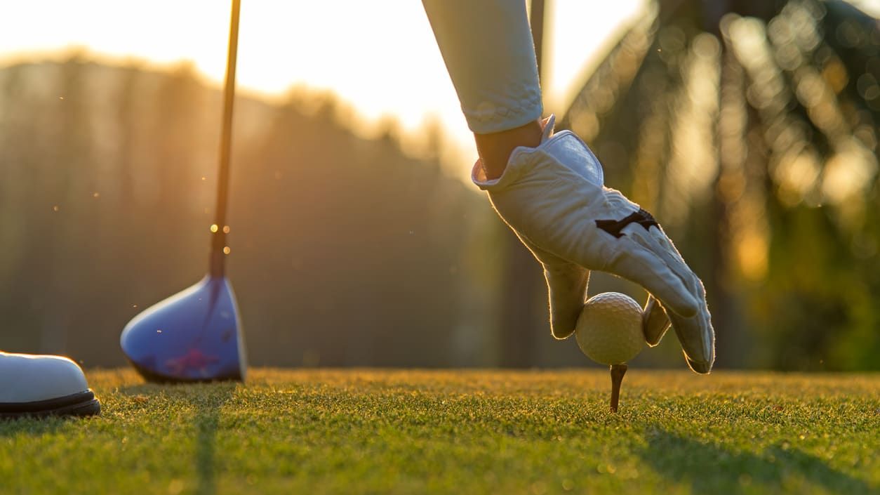 A woman puts down a golf ball.