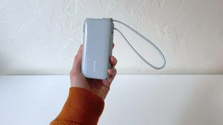 A hand holding the Anker A1637 portable charger in front of a white background