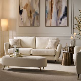 Cream sofa and matching ottoman used as coffee table in living room