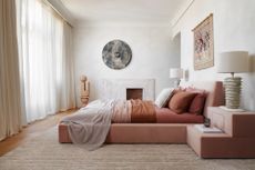 Bright bedroom with pink bed linen, fireplace, and wall art