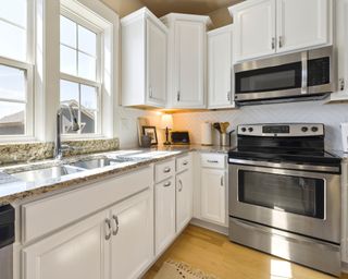 A microwave built into cabinetry in small kitchen with white cabinets
