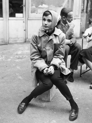 Actress Audrey Hepburn (1929
1993) sitting on a crate near the Eiffel Tower in Paris during the filming of Funny Face in 1956. Co-star Fred Astaire (1899
1987) is behind her.