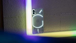 Nothing Phone (1) with its glyph lighting on set against colored lighting