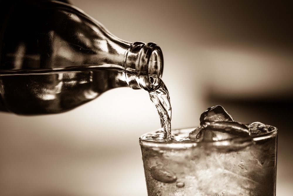 Pouring a clear soda into a glass.