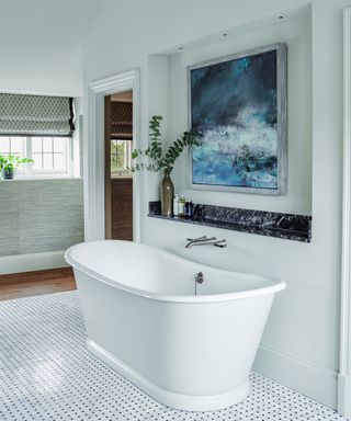white bathroom with freestanding tub and blue artwork