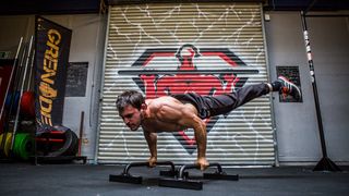 Jase performing a planche calisthenics workout holding two bars with legs in the air in a plank