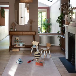 A family living room with toys stored in a console table and scattered on a central rug by the fireplace