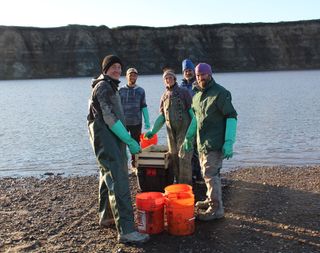 Paleontologists from the University of Alaska Fairbanks pose with buckets full of sediment from the banks of the Colville River