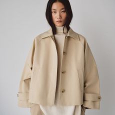 Model wears cropped trench coat, white turtleneck and beige trousers