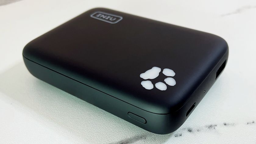 The INIU B43 power bank sits on a marble-effect surface, with the paw print-shaped light angled slightly toward the camera.