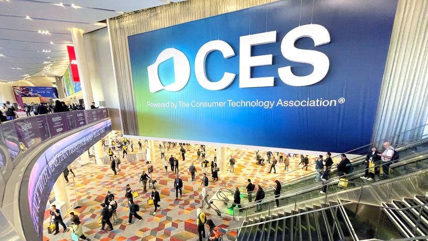 A giant CES show banner hanging above an escalator at CES 2025 with people milling about