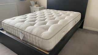 The Simba Earth Escape Mattress on a black wooden bed frame