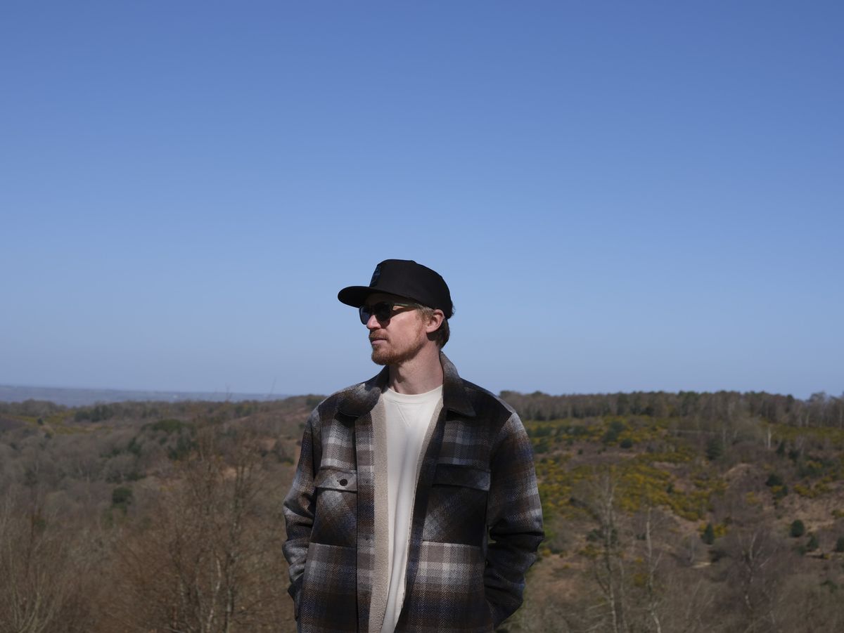Man in baseball cap outside with expansive viewpoint and blue skies