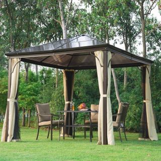 Large beige roofed gazebo on large lawn encloses outdoor dining space