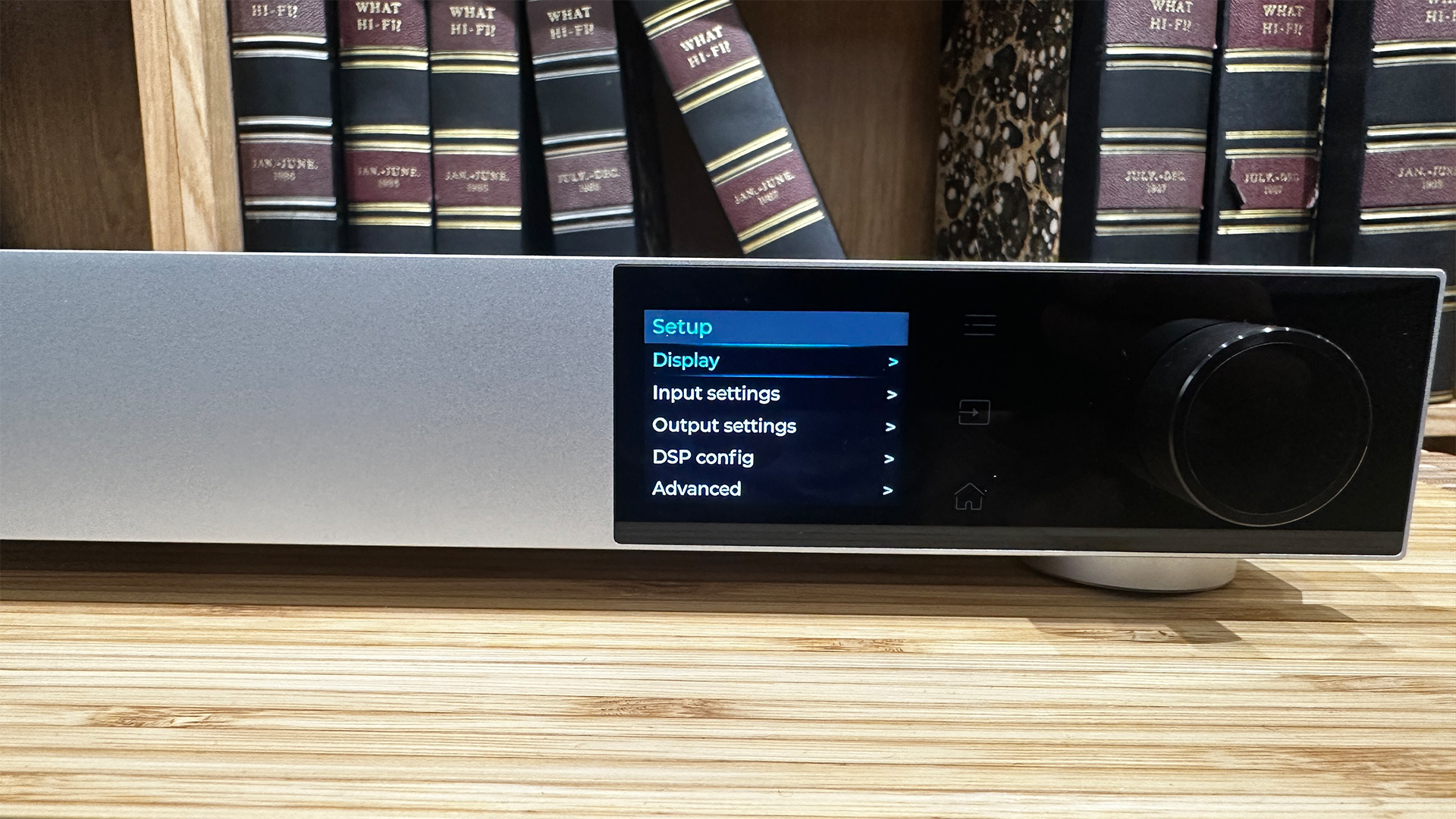 Topping Audio D900 DAC on wooden hi-fi rack in front of bookcase, display is showing menu