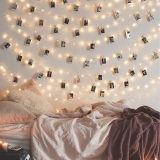 Photo Clip Fairy String Lights above a bed against a white wall.