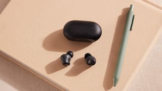 Beats Solo Buds in black on a desk next to a green pen