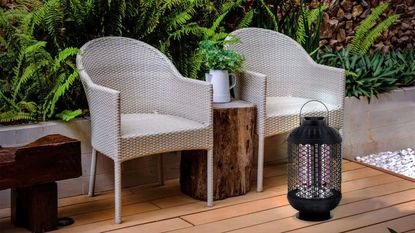 A small lantern electric patio heater on the flloor by two grey rattan outdoor chairs
