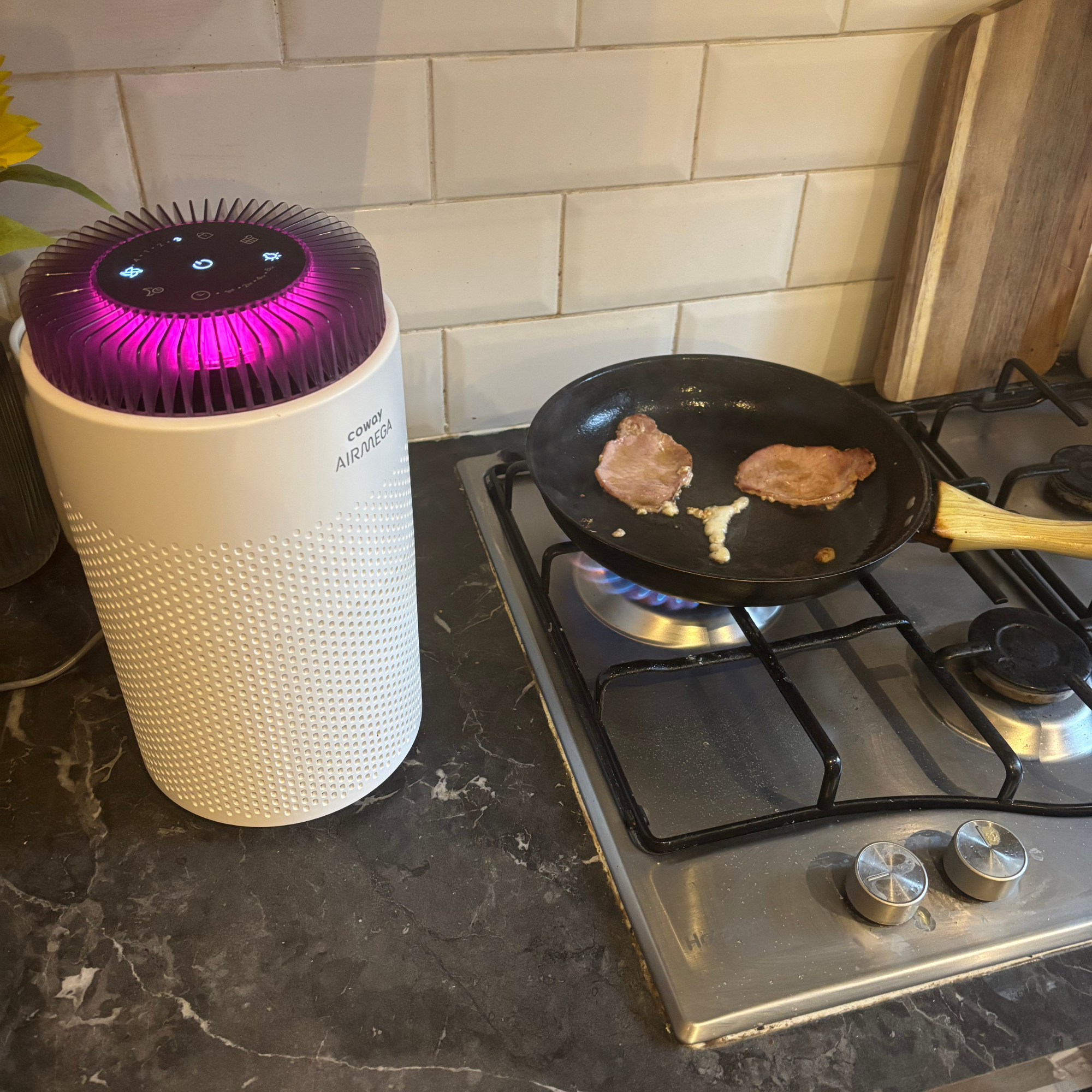 Coway Airmega 50 placed next to frying pan with two rashers of bacon