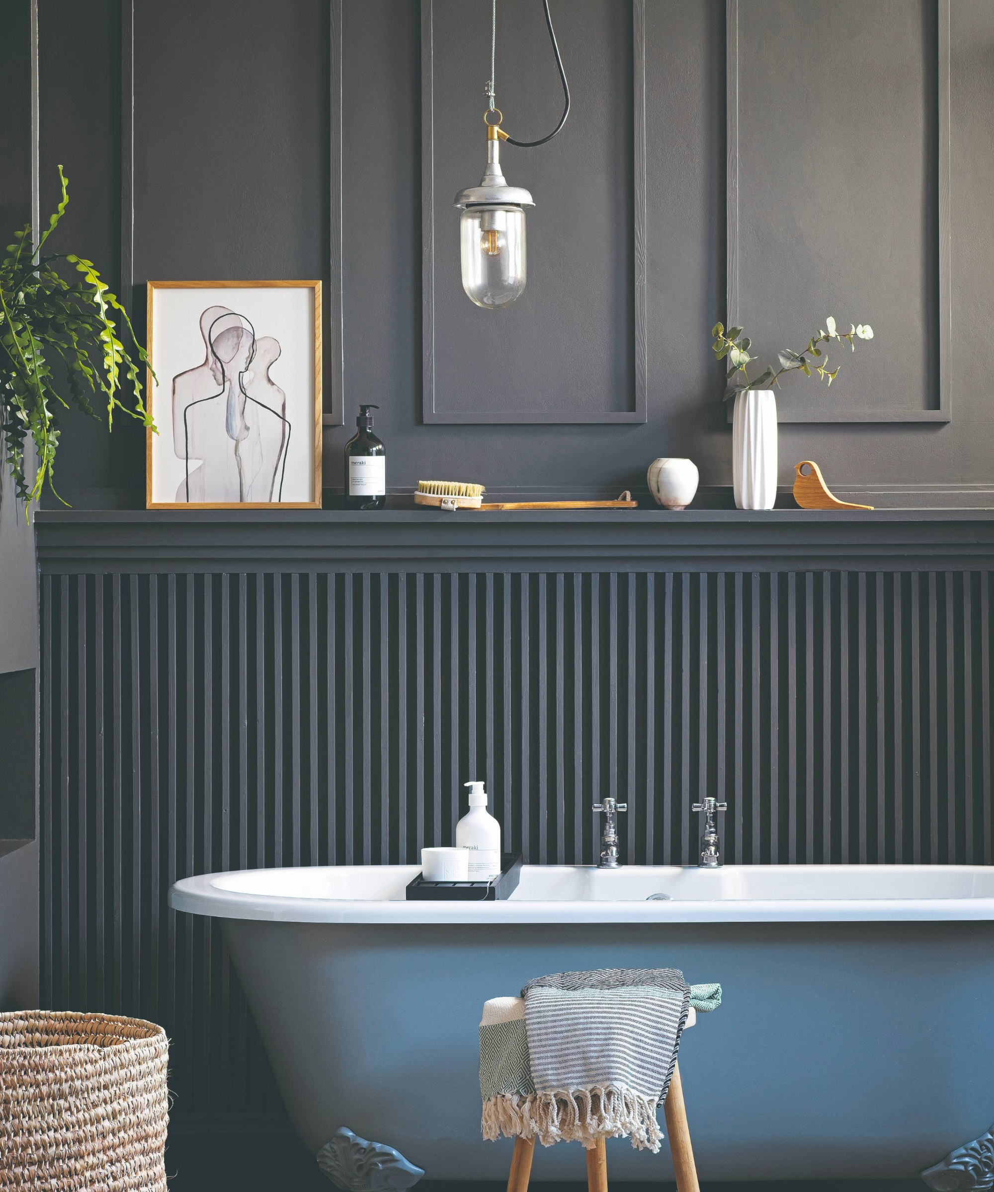 Dark bathroom idea with a pastel blue bathtub and dark grey paneling behind