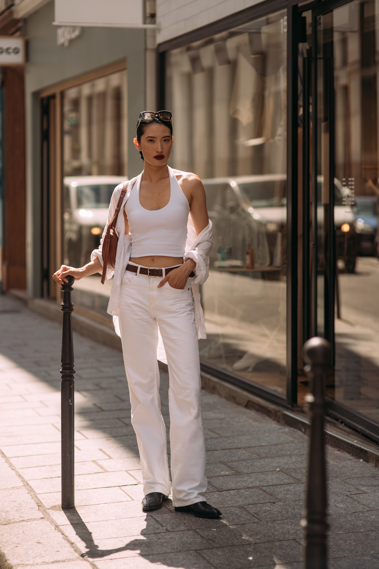 a fashion week attendee wears a white tank top, button down shirt, white jeans