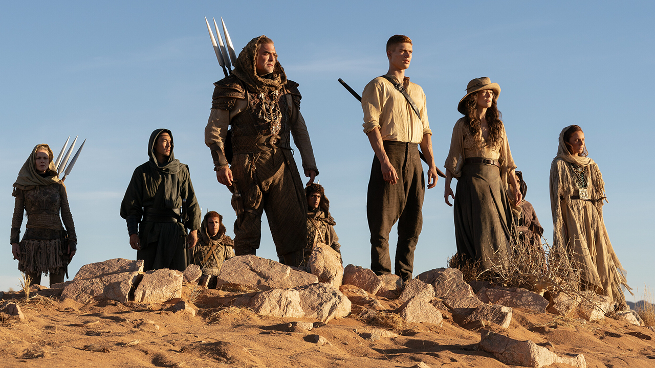 A group of people, including Rand and Morrien, stand on a sandy cliff on the wheel of Time Season 3