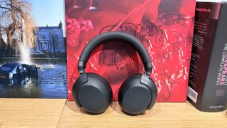 Philips TAH8000E headphones on a desk with red and blue vinyl albums in the background