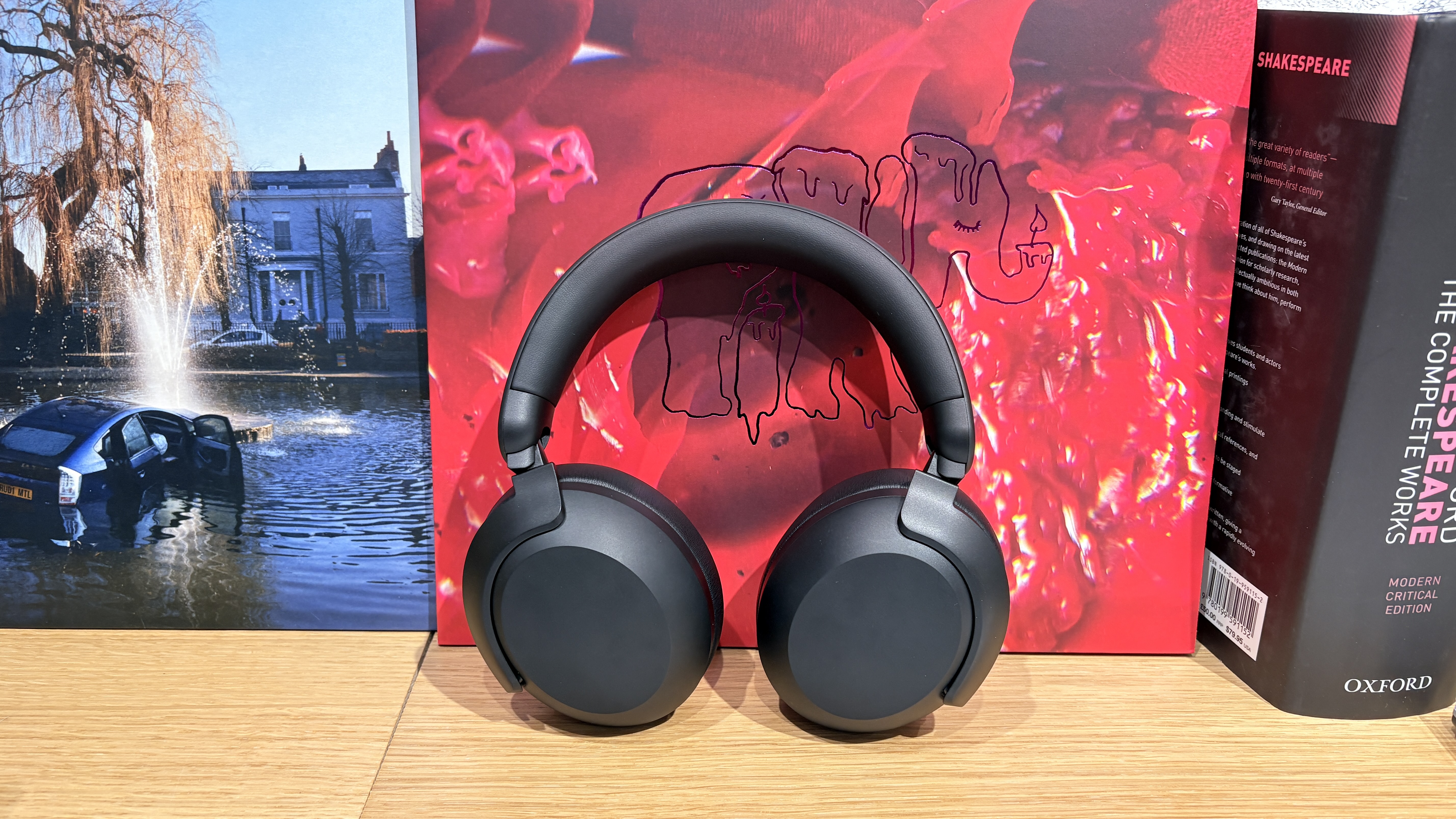 Philips TAH8000E headphones on a desk with red and blue vinyl albums in the background