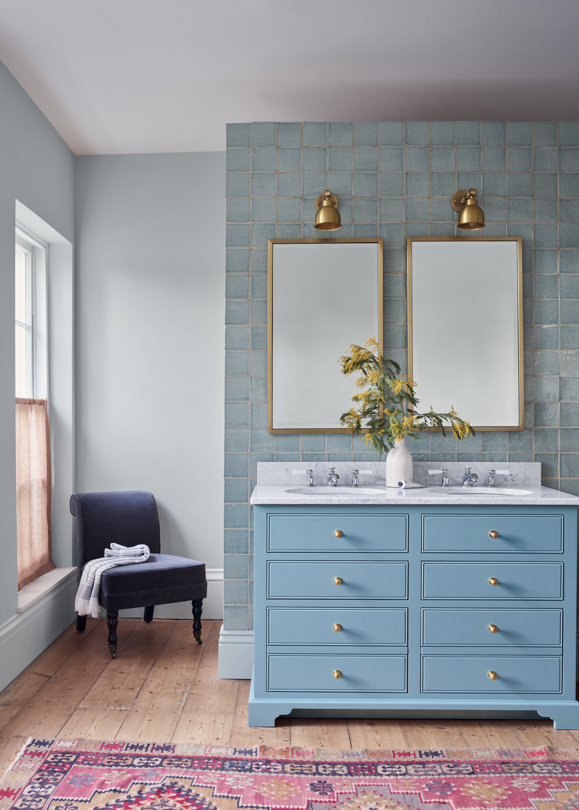 bathroom with light blue walls, vanity unit, and feature wall tiles with a double sink and mirrors