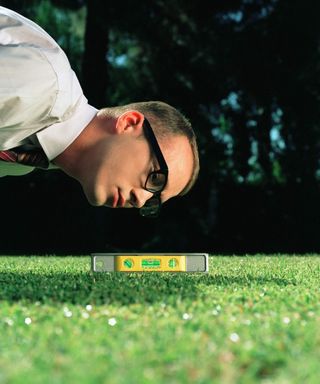 A man checking the level of a lawn with a spirit level