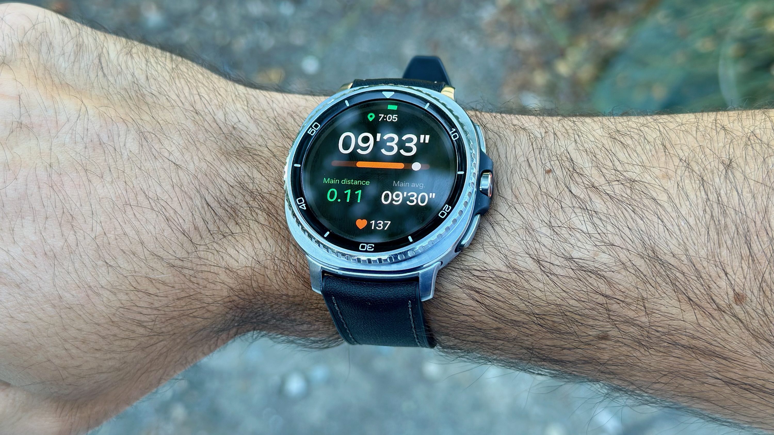 The Samsung Galaxy Watch 8 Classic on a wrist showing a Running Coach workout screen with current pace, distance, average pace, heart rate, and time.