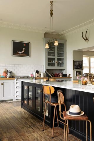 A kitchen by deVOL with grey cabinets and black island with glass panes