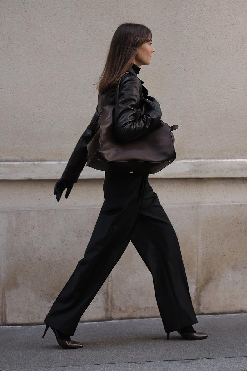 Woman wearing a black coat and brown bag.