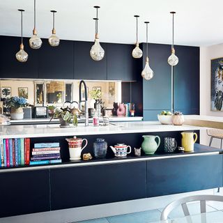 dark blue kitchen with island and bare bulb pendant lights