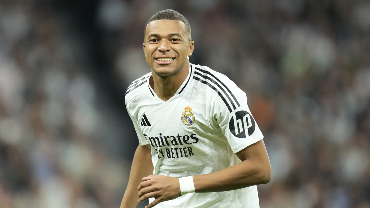 Kylian Mbappe centre-forward of Real Madrid and France, wearing white Real Madrid football kit and smiling broadly, in anticipation of Real Madrid vs Barcelona – the first El Clasico of 2024/25 La Liga season.