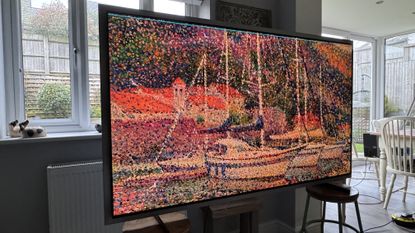 The Samsung S99H/S95H TV in a home, showing artwork of a boat on the screen in an impressionist style