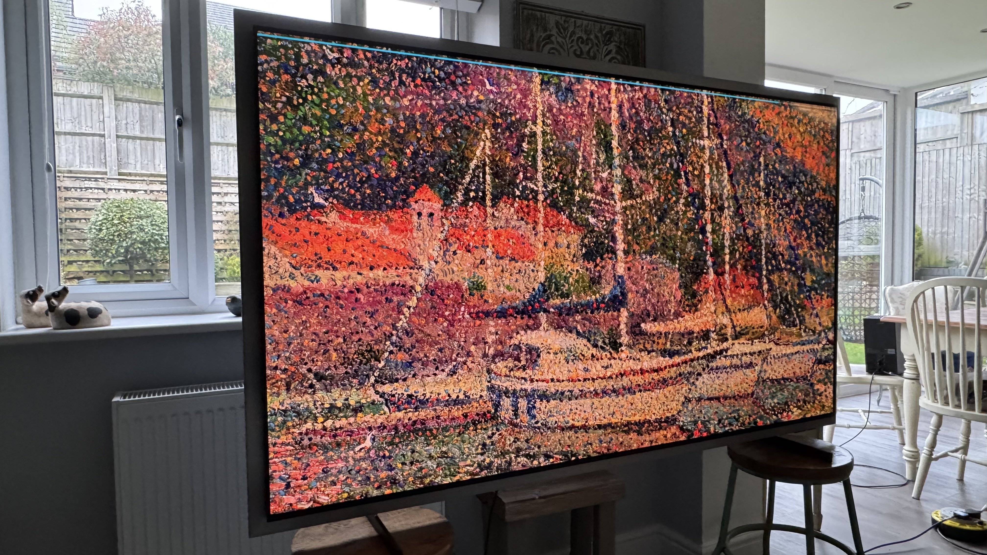 The Samsung S99H/S95H TV in a home, showing artwork of a boat on the screen in an impressionist style