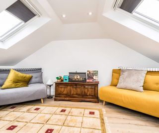 A sitting room, with two sofa beds and a large rug, sitting under two rooflights, in a loft conversion undertaken by Econoloft