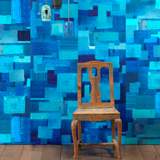 Painted chair on wooden floor in front of blue wallpaper