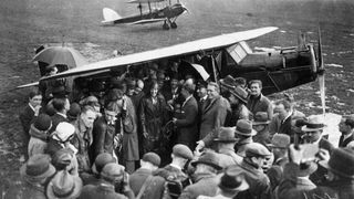 Amelia Earhart is surrounded by a crowd of wellwishers and pressmen upon her arrival at Hanworth airfield after crossing the Atlantic. In this photo, she is being congratulated by Andrew Mellon, U.S. ambassador to Britain.