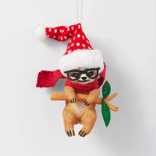 A Christmas ornament of a sloth wearing glasses and a Santa hat