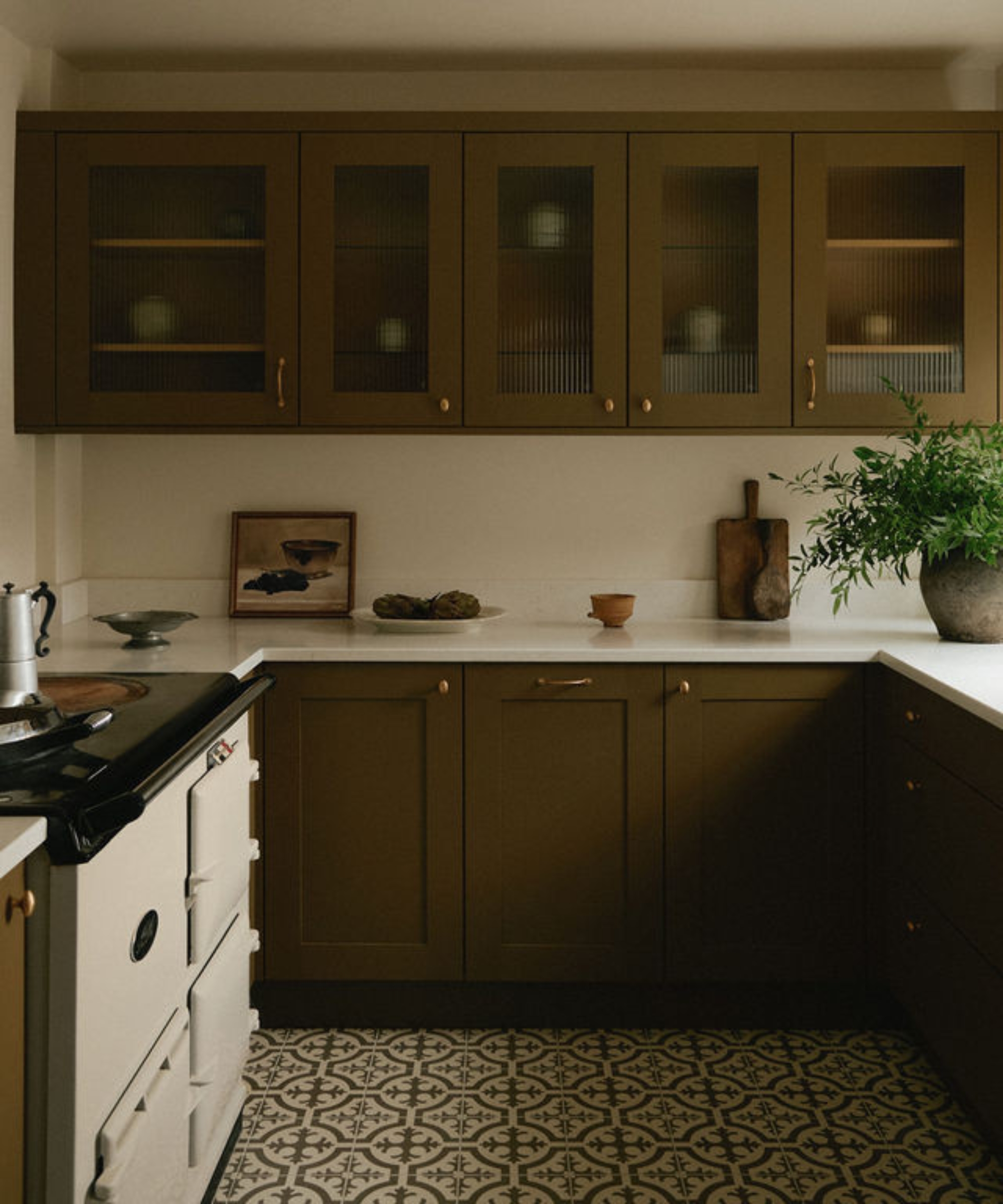 An olive green cottagecore kitchen with white countertops and a white aga and a cream and cream patterned floor