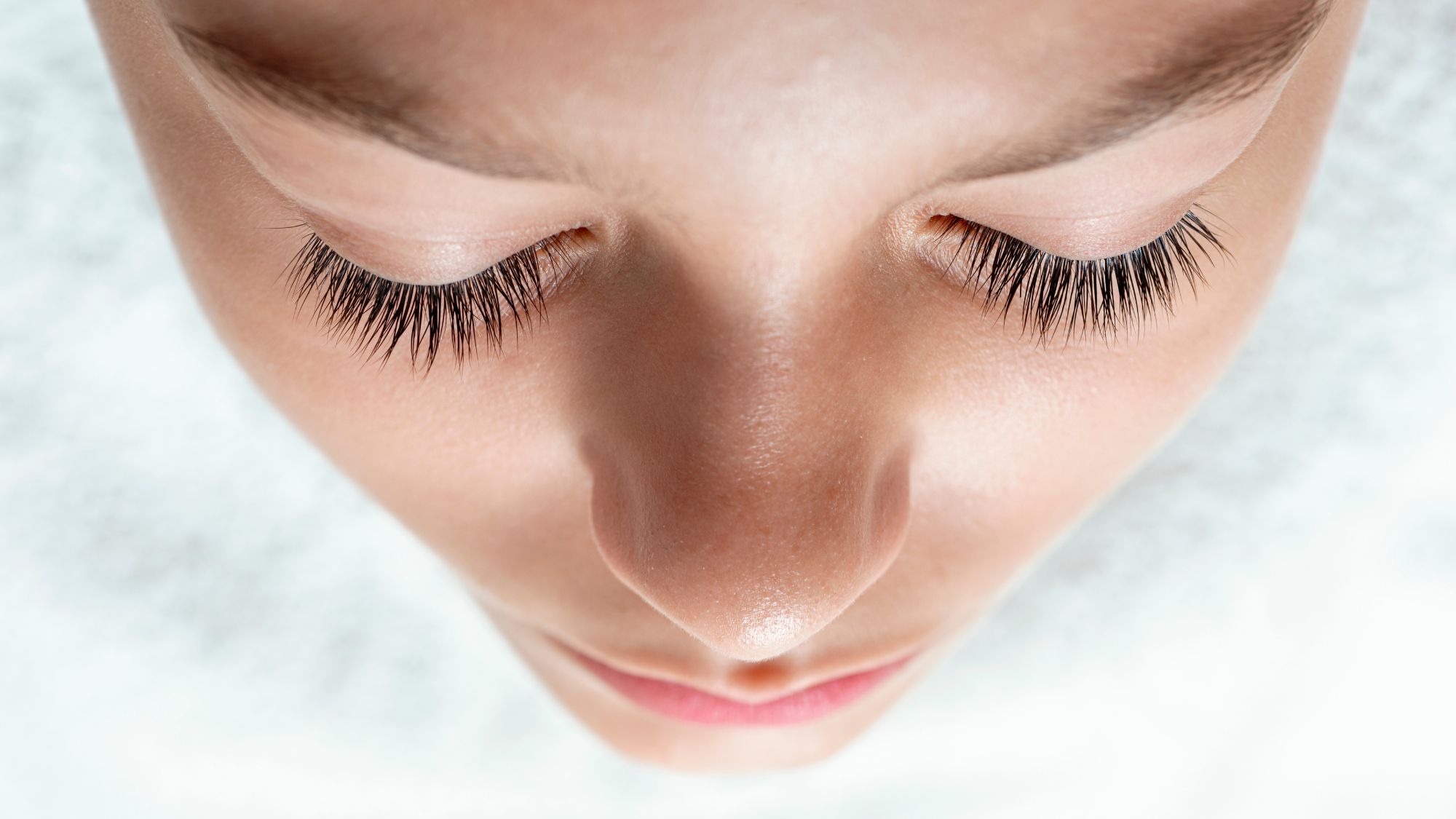 A woman&#039;s face shot from above showing beautiful long lashes