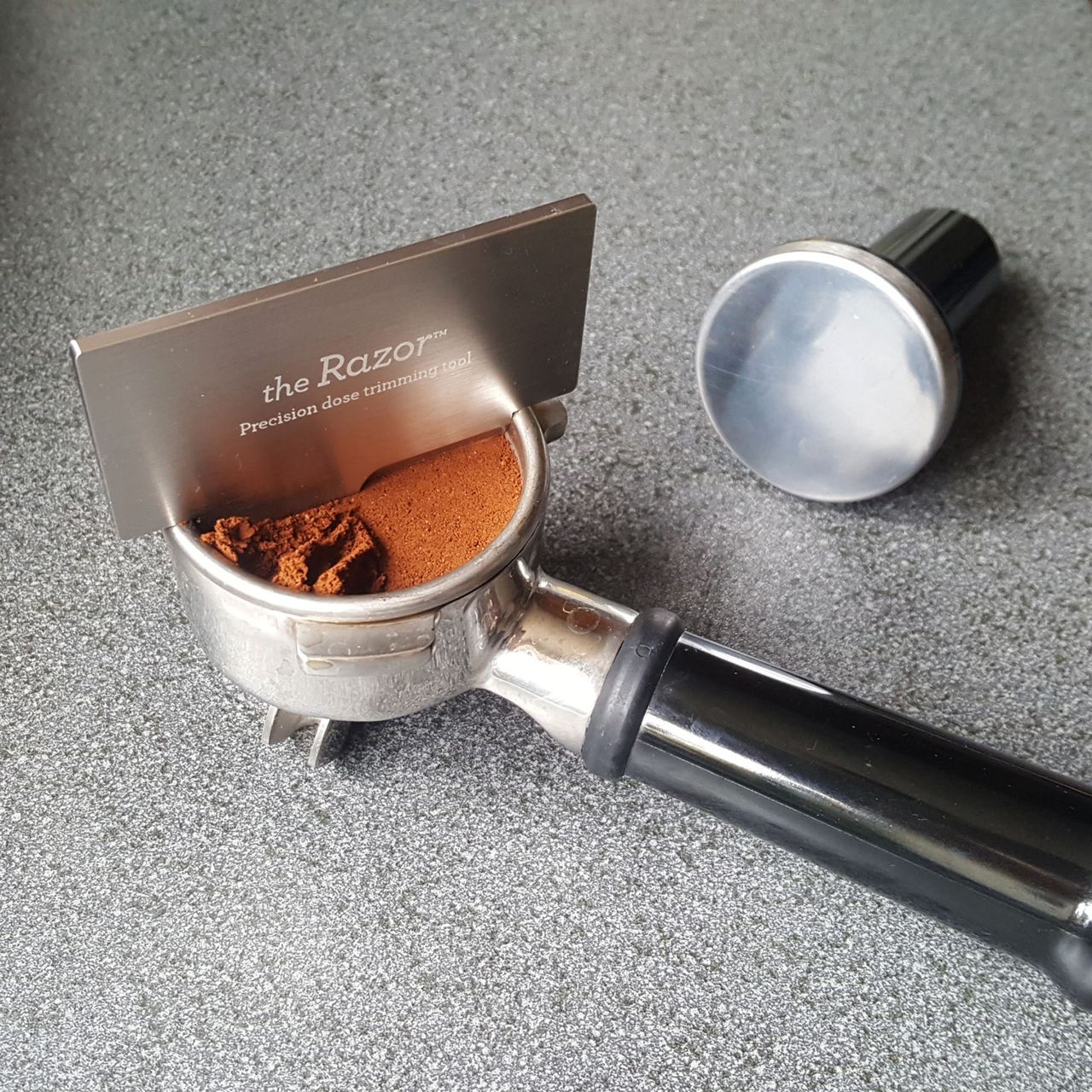 A close up of the portafilter and razor tool that come with the Sage Barista Express coffee machine